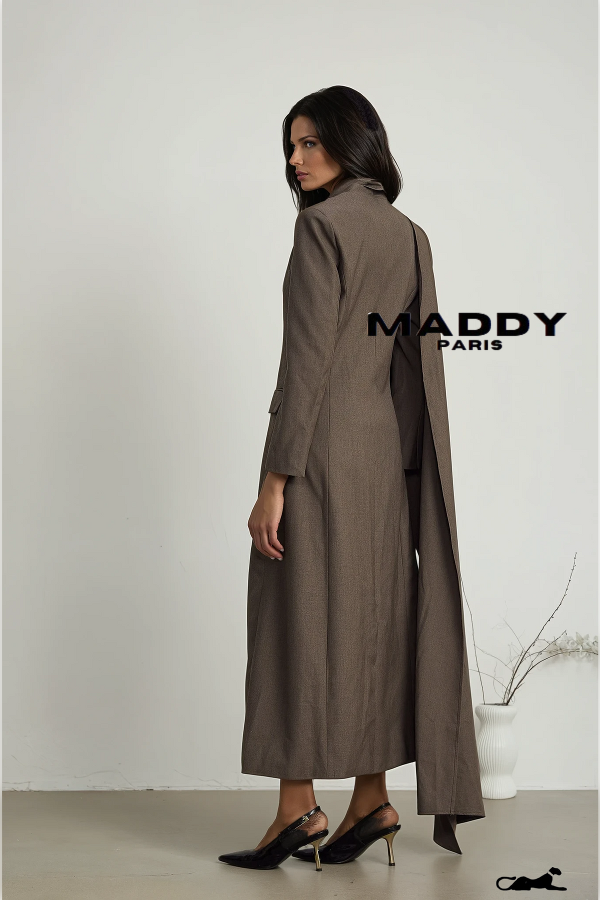 Woman wearing a long brown coat with 'MADDY PARIS' branding on a white background