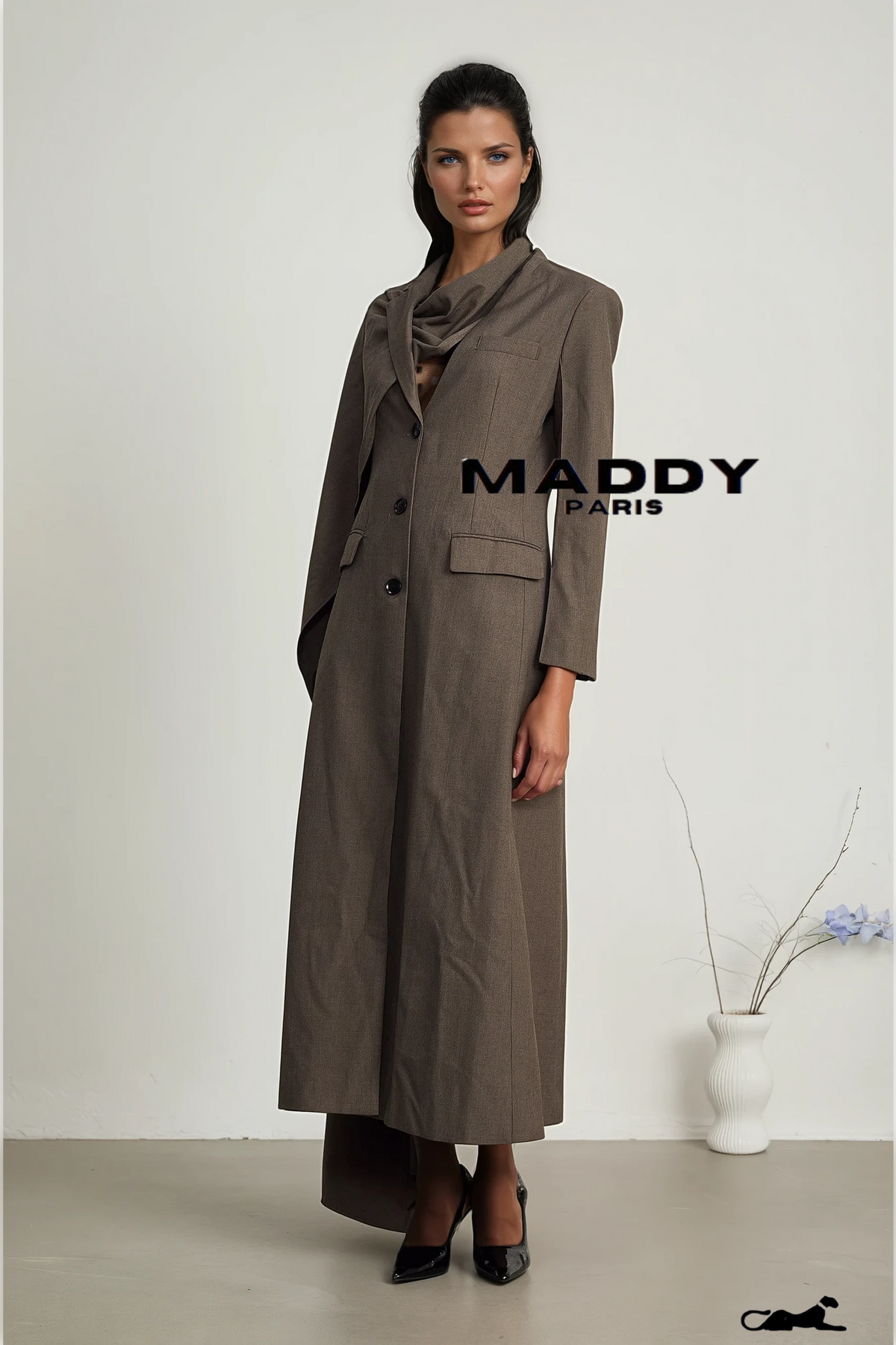 Woman wearing a long brown coat with 'MADDY PARIS' branding on a white background.